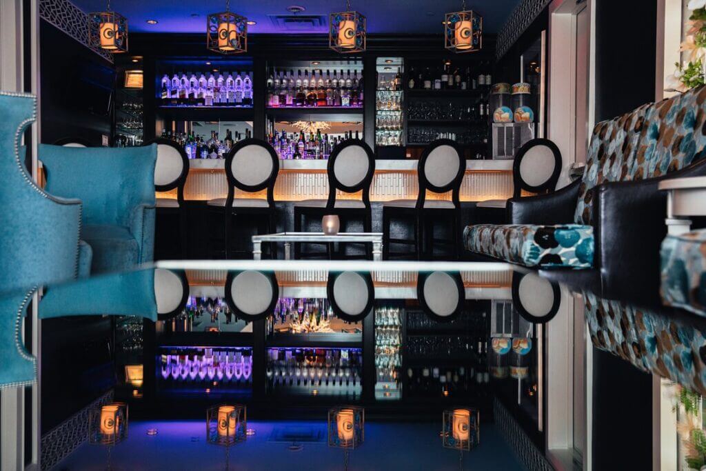 The Blue Lounge bar with backlit bottle shelves and a row of round-back stools