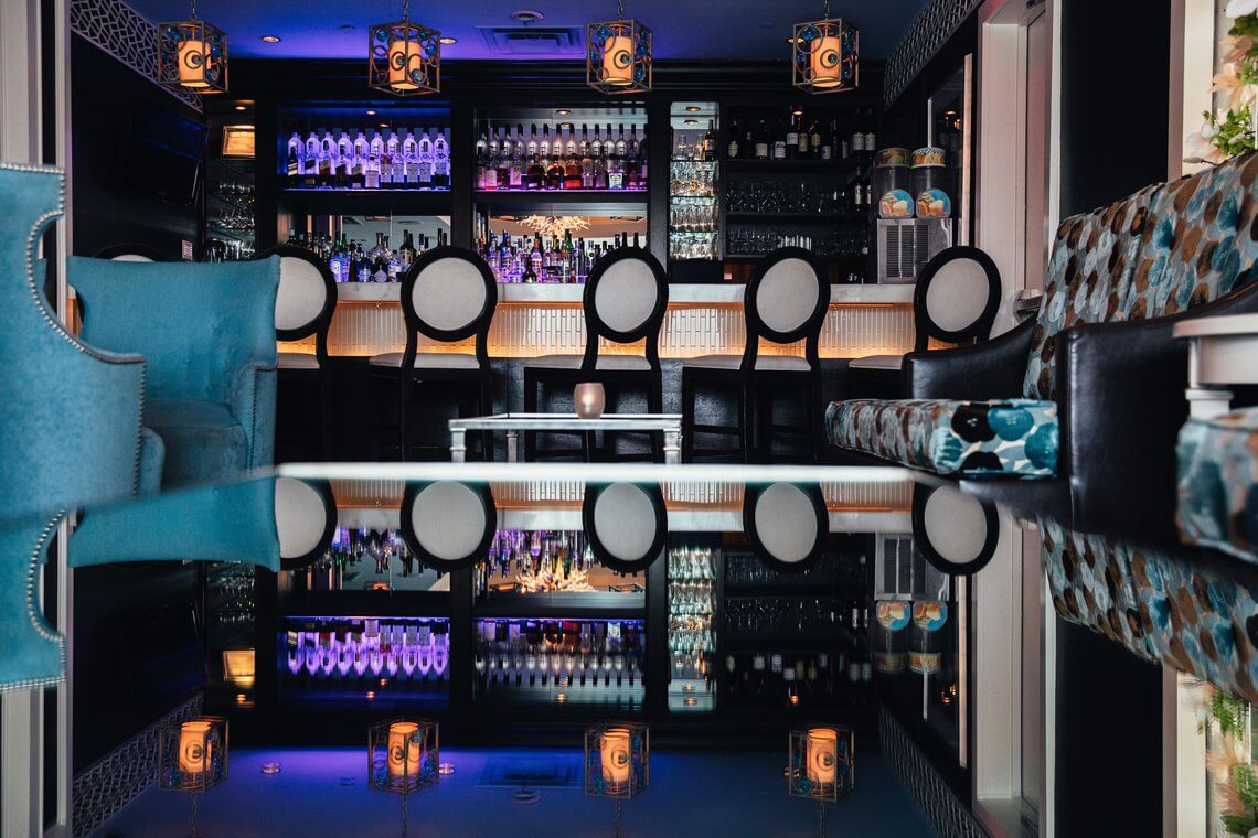 The Blue Lounge bar with backlit bottle shelves and a row of round-back stools