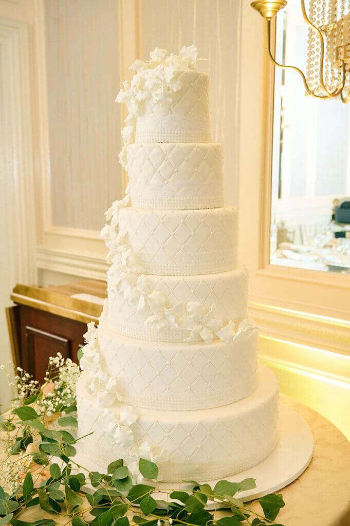 Tall white wedding cake decorated with sugar flowers