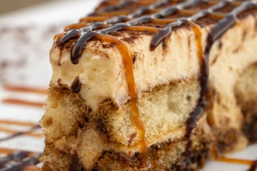 Slice of tiramisu with chocolate and caramel drizzle