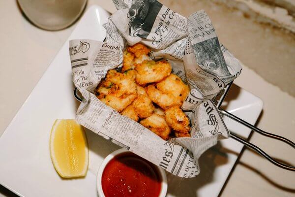 Fried seafood in a paper-lined basket with lemon and marinara