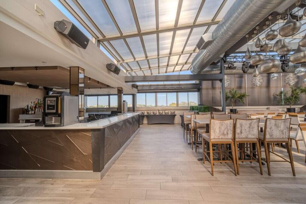 The Rooftop Lounge bar and high-top tables under the retractable glass roof