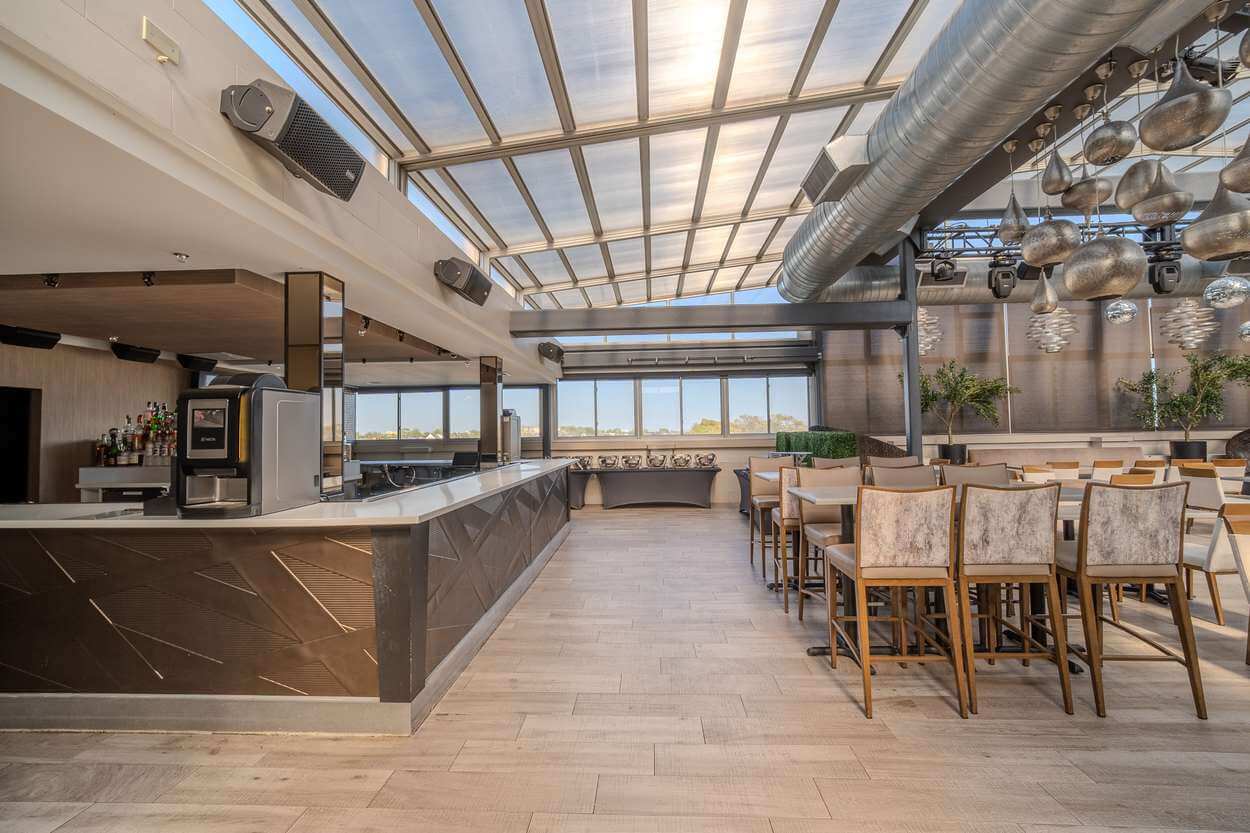 The Rooftop Lounge bar and high-top tables under the retractable glass roof