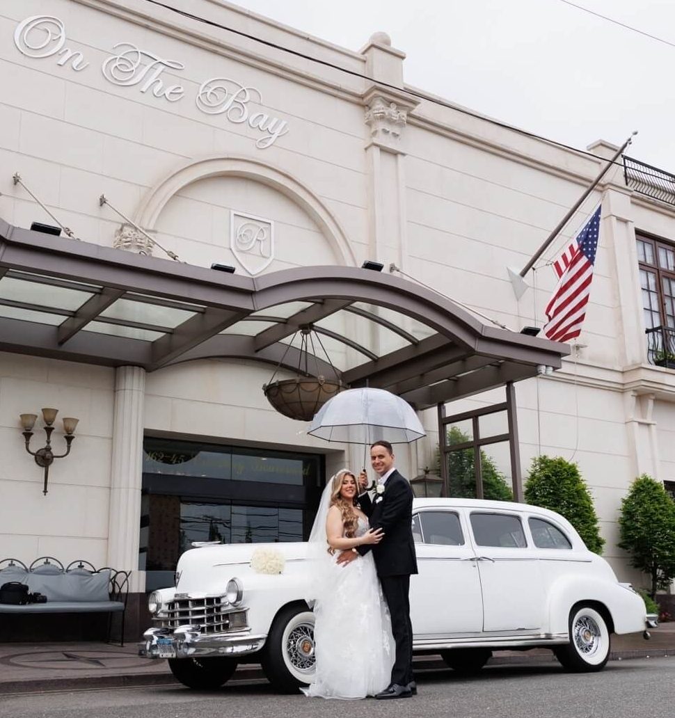 A bride and groom with a white vintage car outside Russo’s On The Bay